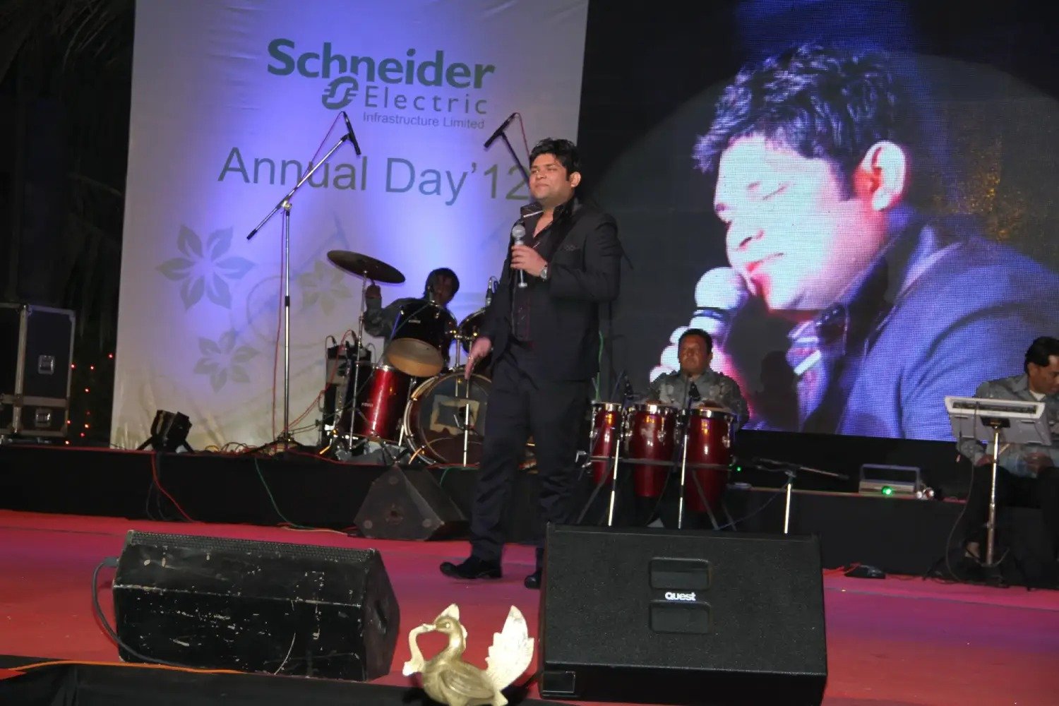 Man and woman speaking on stage at night with blue lighting